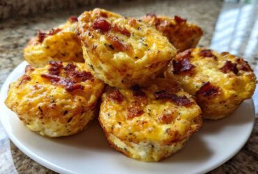 A stack of five golden brown bacon egg bites served on a small white plate.