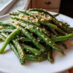 Close-up of bright green beans seasoned and topped with crunchy breadcrumbs or nuts.