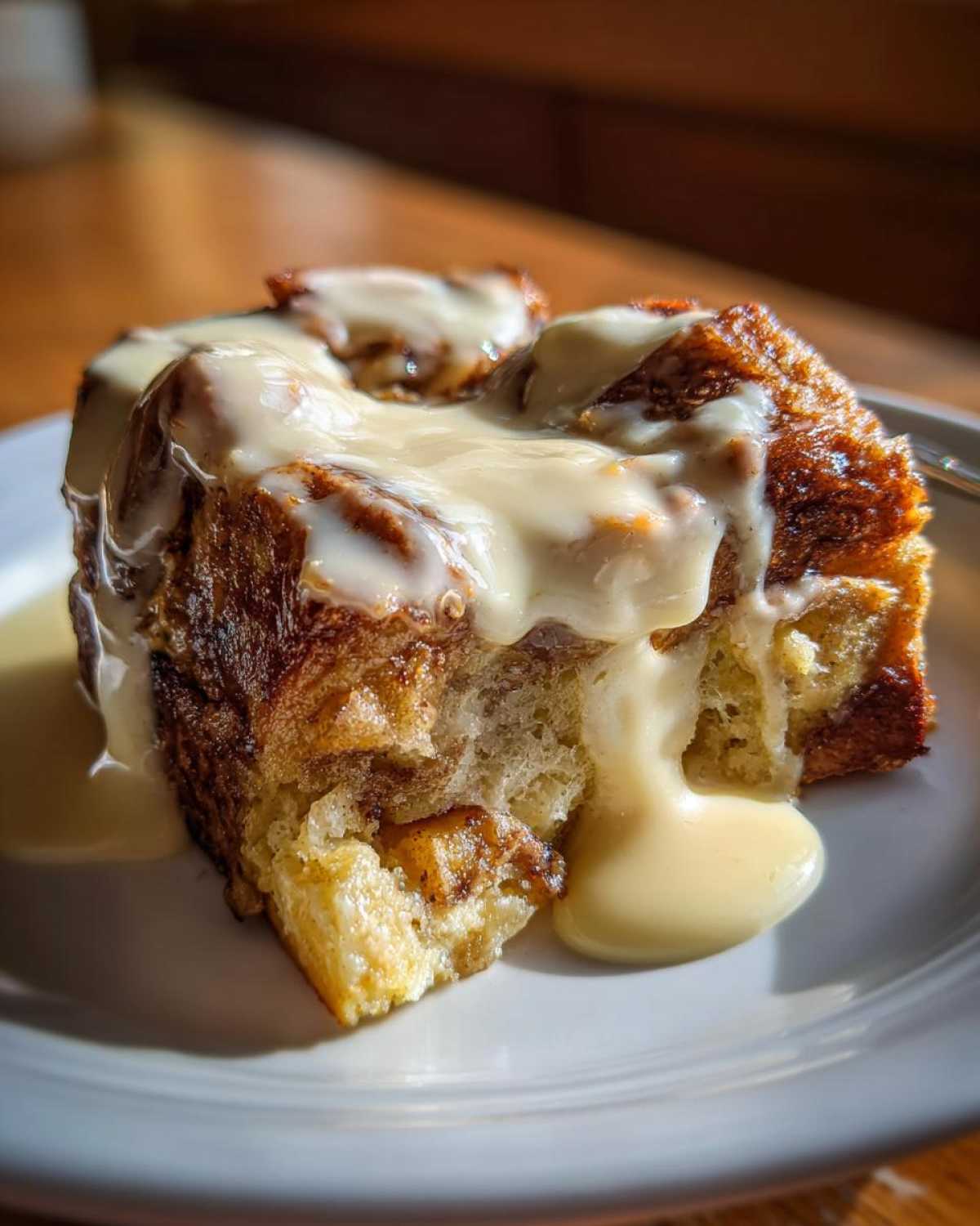 Close-up of a moist slice of bread pudding covered in thick vanilla sauce.