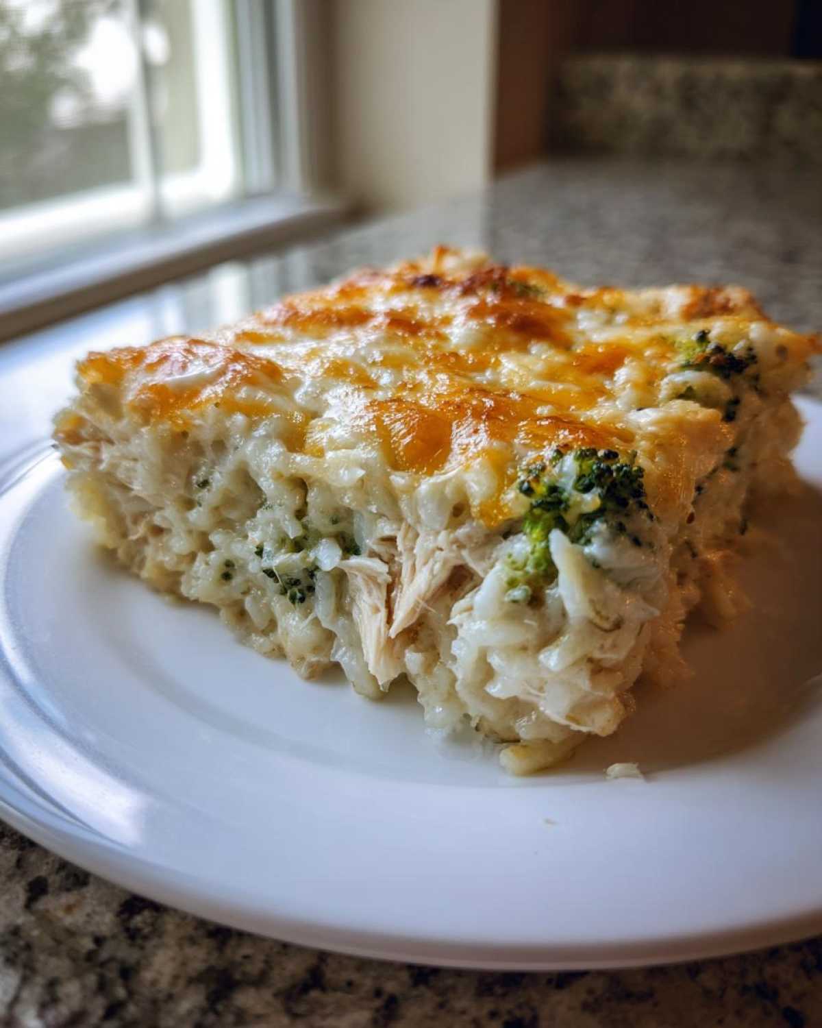 A generous slice of creamy chicken broccoli rice casserole with a golden, melted cheese topping.