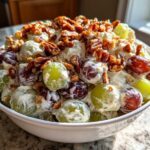 A white bowl filled with creamy chicken salad chick grape salad, topped with toasted pecans.