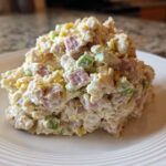 A generous scoop of creamy ham salad featuring diced ham, celery, and egg yolk served on a white plate.