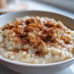 Close-up of a bowl of creamy rice pudding generously dusted with ground cinnamon.