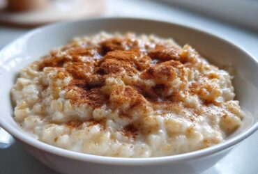 Close-up of a bowl of creamy rice pudding generously dusted with ground cinnamon.