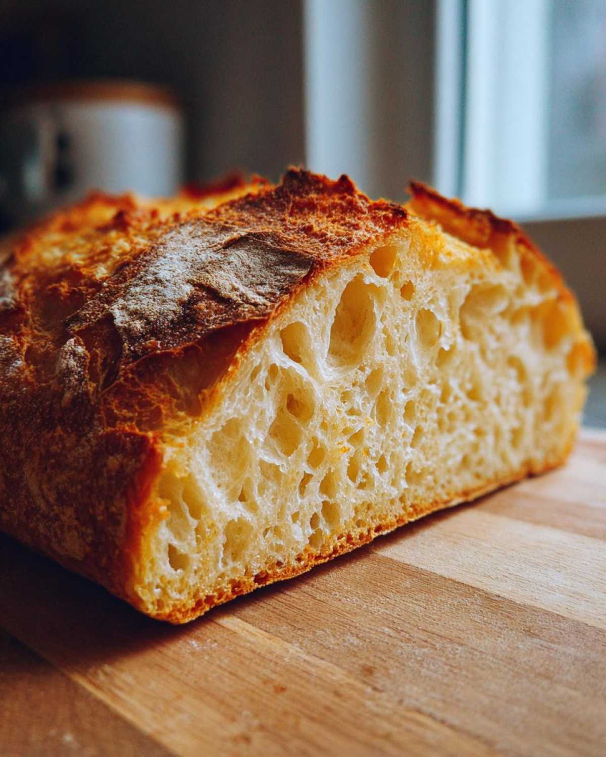 Close-up of a freshly baked Italian bread loaf cut in half, showing a beautiful open, airy crumb structure and golden crust.