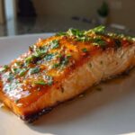 A perfectly cooked fillet of salmon glazed with honey garlic sauce and topped with fresh parsley.