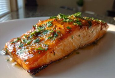 A perfectly cooked fillet of salmon glazed with honey garlic sauce and topped with fresh parsley.