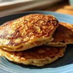 A stack of three perfectly cooked, golden-brown banana pancakes resting on a blue plate.