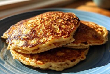 A stack of three perfectly cooked, golden-brown banana pancakes resting on a blue plate.
