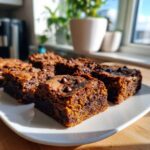 Close-up of fudgy sweet potato brownies topped with chocolate chips on a white plate.