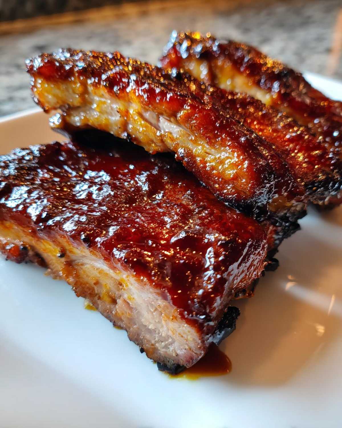 Close-up of three pieces of tender, glazed pork steak covered in a thick, shiny barbecue sauce.