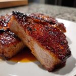 Close-up of a thick, tender pork steak recipe cut showing a caramelized, glossy glaze and moist interior.
