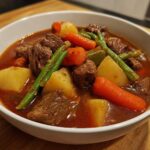 Close-up of a hearty bowl of vegetable beef soup featuring tender beef chunks, potatoes, carrots, and green beans.