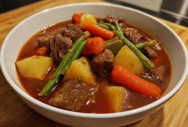 Close-up of a hearty bowl of vegetable beef soup featuring tender beef chunks, potatoes, carrots, and green beans.