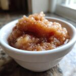 Close-up of chunky, cinnamon-spiced homemade applesauce served in a small white bowl.