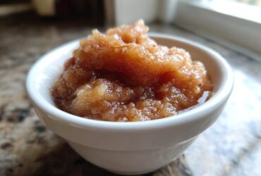 Close-up of chunky, cinnamon-spiced homemade applesauce served in a small white bowl.
