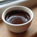 A close-up of rich, dark homemade chocolate pudding set in a small white ramekin.