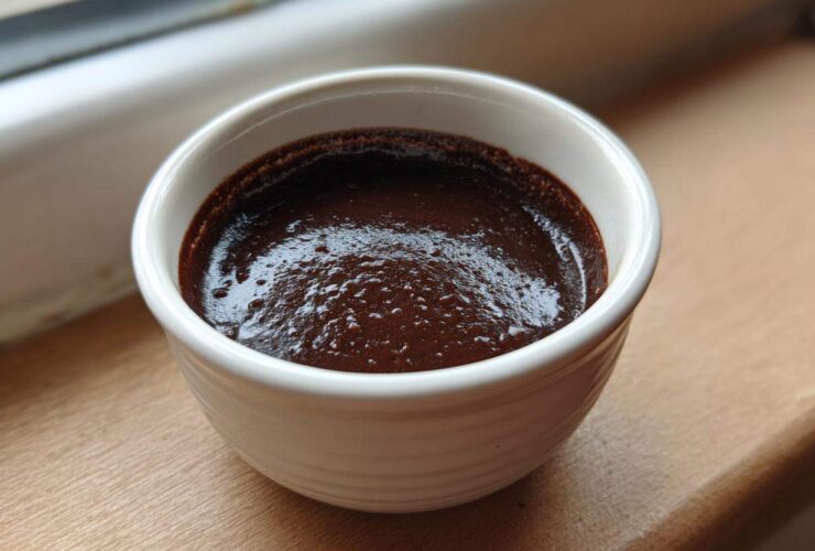 A close-up of rich, dark homemade chocolate pudding set in a small white ramekin.