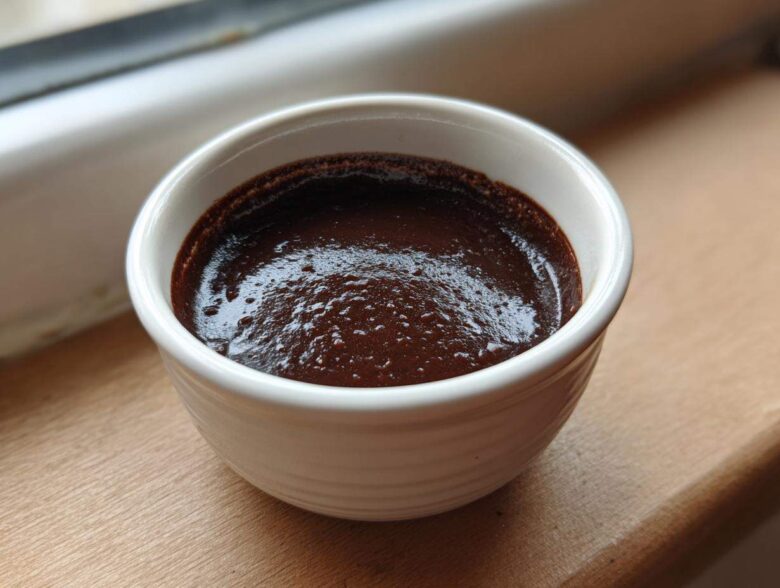 A close-up of rich, dark homemade chocolate pudding set in a small white ramekin.