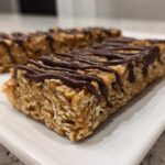 Close-up of homemade protein bars made with oats, drizzled generously with dark chocolate.