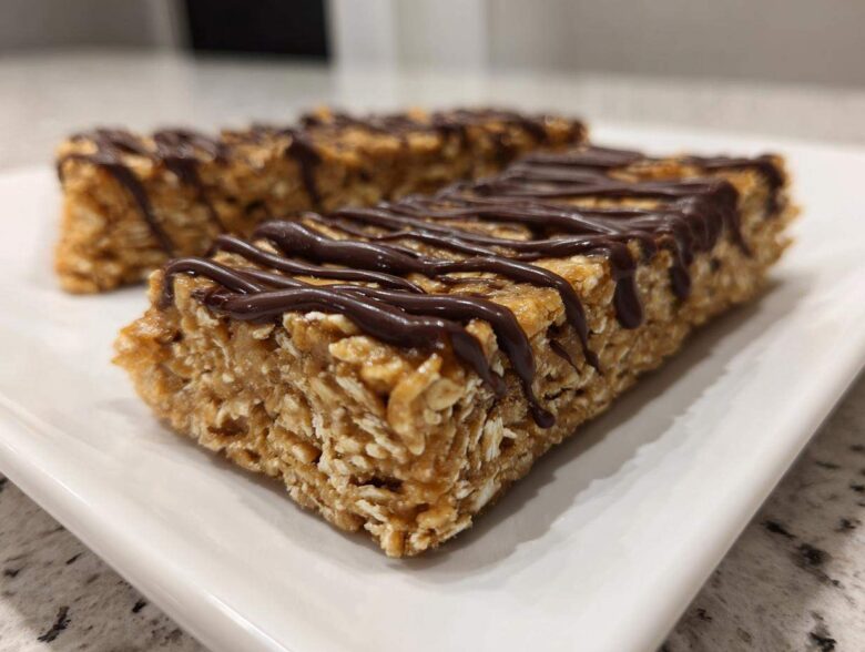 Close-up of homemade protein bars made with oats, drizzled generously with dark chocolate.