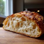Cross-section showing the open, airy crumb structure of the amazing 5-minute Italian bread with a dark, crusty top.