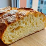 Close-up of the airy, open crumb structure inside a freshly baked Italian bread loaf.