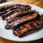 Close-up of perfectly grilled and sliced steak showing a medium-rare center, coated in the rich carne asada marinade.