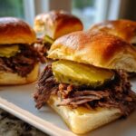 Four delicious Mississippi pot roast sliders piled high with shredded beef and topped with a thick pickle slice on brioche buns.