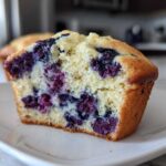 Close-up of a moist blueberry protein muffins cut in half, showing the fluffy interior and burst blueberries.