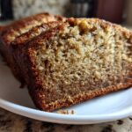 Close-up of moist, golden brown slices of sugar free banana bread served on a small white plate.