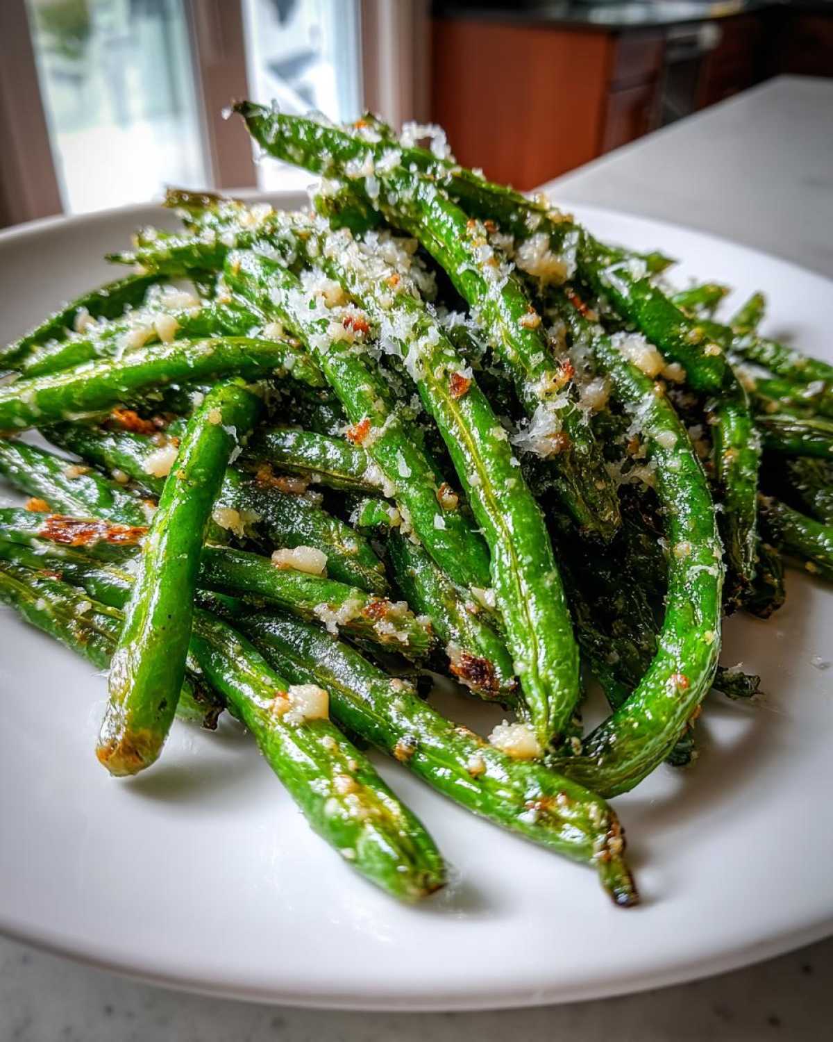 Close-up of bright green beans tossed with garlic and grated Parmesan cheese.