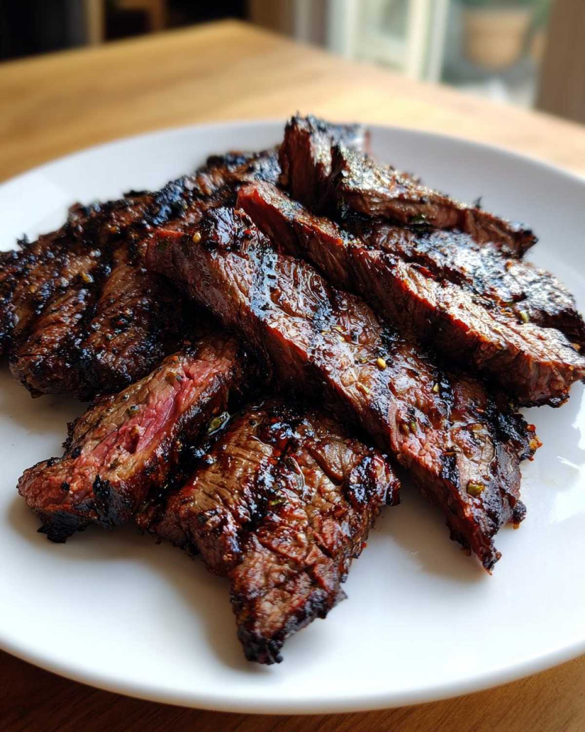 Slices of juicy, grilled steak showing a medium-rare center, prepared using the carne asada marinade.