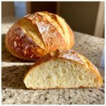 A loaf of homemade soft french bread, partially sliced to show the airy, open crumb structure.
