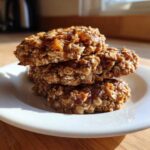 A stack of three homemade 2-ingredient breakfast cookie oat rounds on a white plate.