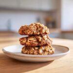 Three golden brown breakfast cookie stacked on a small ceramic plate, ready to eat.