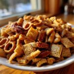 A mound of homemade toffee chex mix recipe featuring Chex cereal, pretzels, and pecans coated in a shiny toffee glaze.