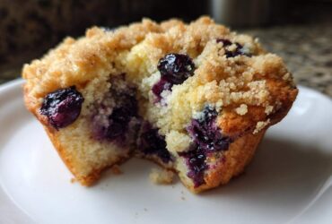Close-up of a delicious blueberry muffin cut in half showing moist interior, bursting blueberries, and crumb topping.