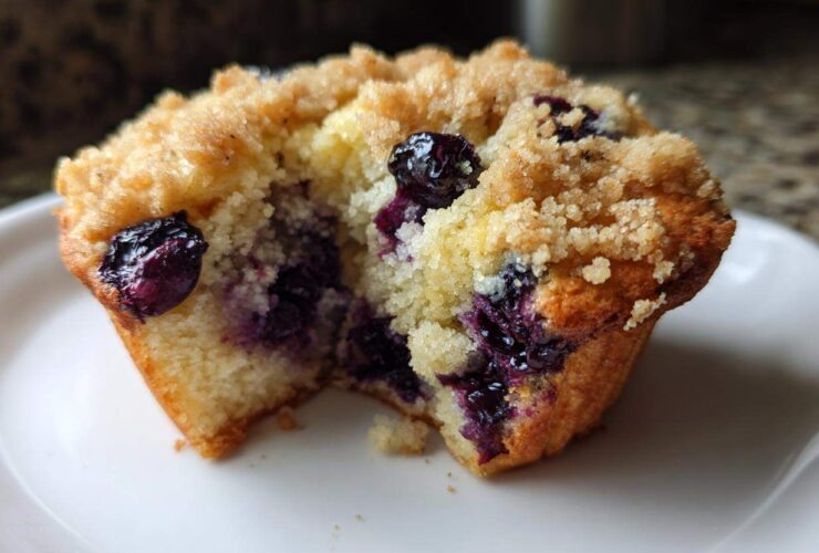 Close-up of a delicious blueberry muffin cut in half showing moist interior, bursting blueberries, and crumb topping.