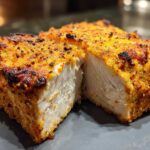Close-up of a seasoned, crispy air fryer chicken breast cut in half showing juicy white meat inside.