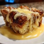 Close-up of a square portion of amazing bread pudding topped with thick vanilla sauce.