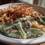 A close-up view of a creamy green bean casserole topped generously with crispy fried onions.