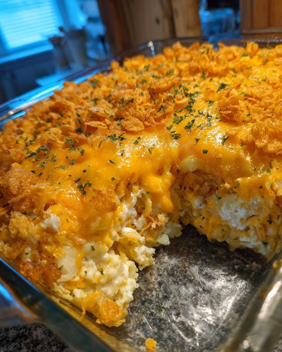 A close-up of a baked hashbrown casserole with melted cheddar cheese and a crunchy cornflake topping.