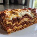 Close-up of a thick, cheesy slice of amazing lasagna featuring layers of pasta, rich meat sauce, and browned cheese topping.