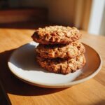 A stack of three golden brown oatmeal cookie treats sitting on a small ceramic plate.