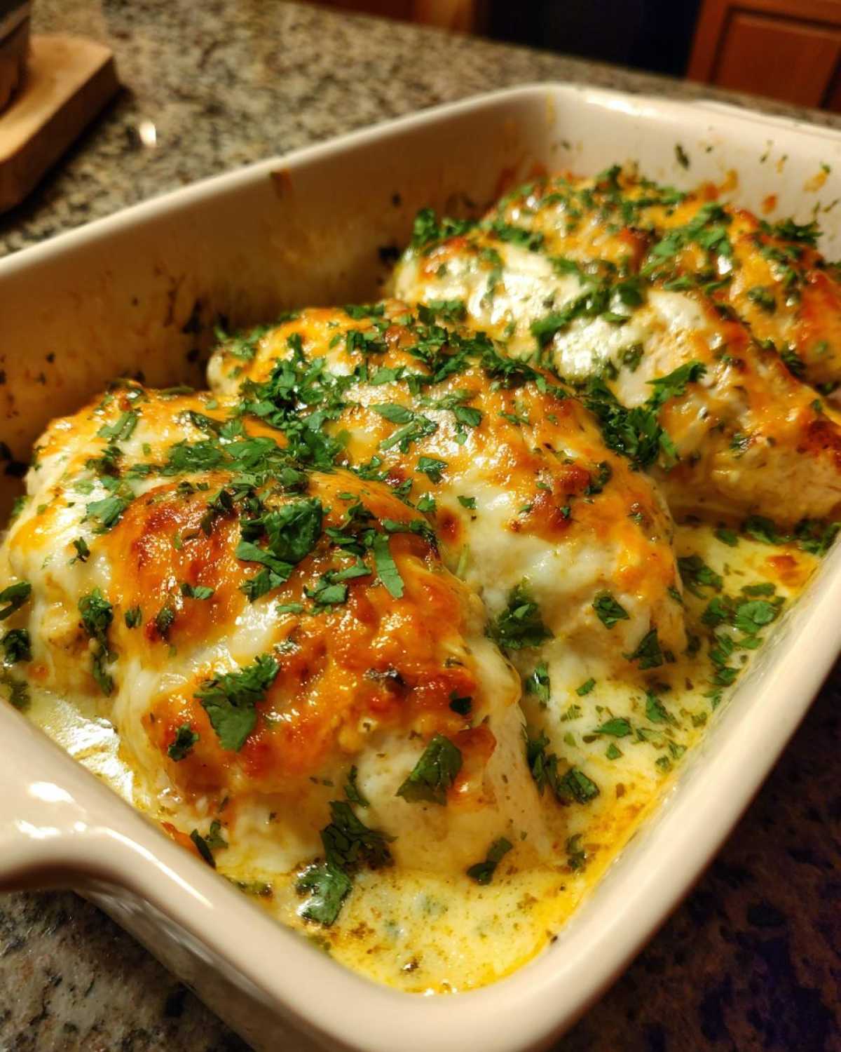 Baked fiesta lime chicken breasts covered in melted cheese and fresh cilantro in a casserole dish.