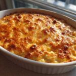 A creamy, baked popper dip with a bubbly, golden-brown cheesy crust in a white oval baking dish.
