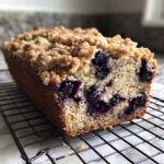 Close-up of a freshly baked blueberry banana bread loaf with a thick, crunchy streusel topping.