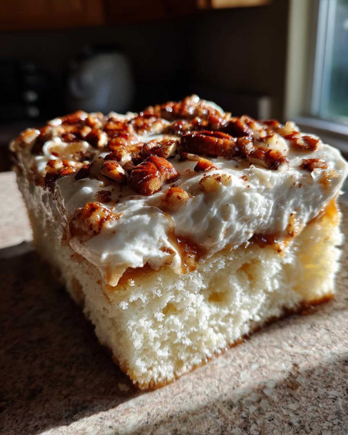 A close-up slice of moist butter pecan praline poke cake topped with whipped cream and candied pecans.