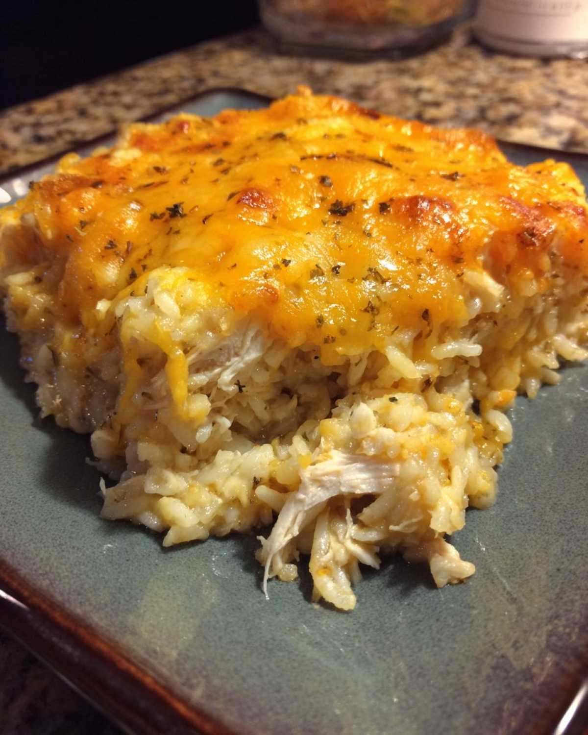 A close-up serving of creamy chicken and rice casserole topped with melted cheddar cheese.